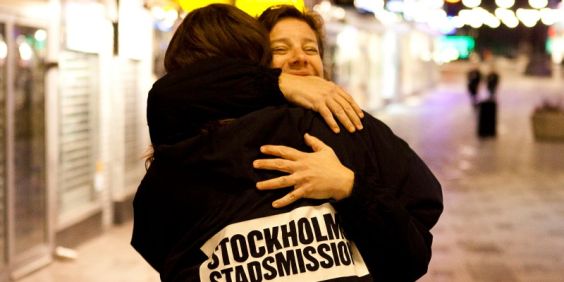En medarbetare från Stockholms Stadsmission kramar en människa på stan.
