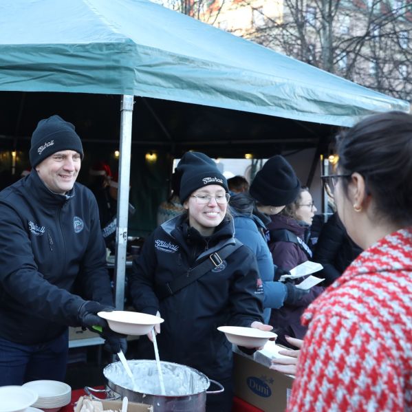 Medarbetare på ICA Nacka serverar mat under Stockholms Stadsmissions jullunch.