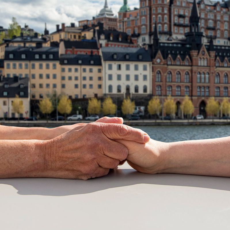 Två människor håller händerna med Stockholm i bakgrunden.