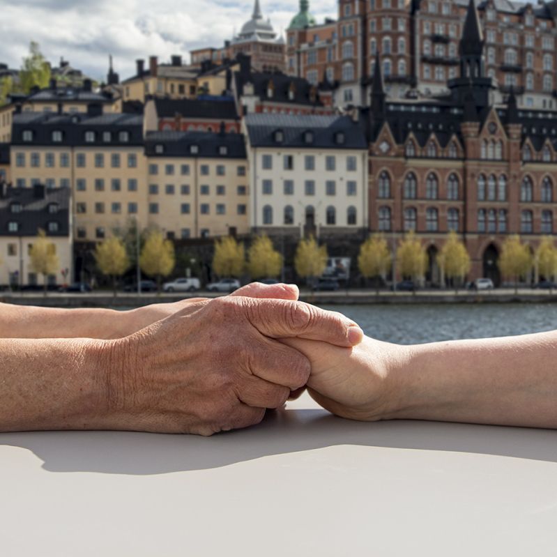 Två människor håller händerna med Stockholm i bakgrunden.