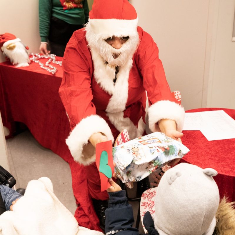 Jultomte ger en julkapp till ett barn på en av Stockholms Stadsmissions mötesplatser.