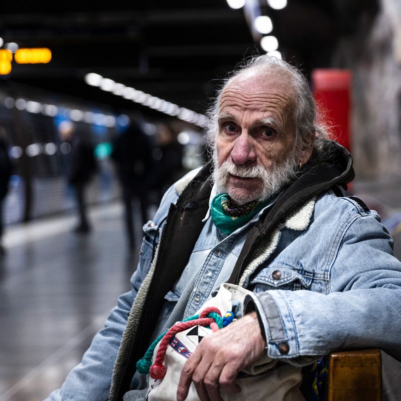 En man sitter på en bänk på en tunnelbanestation.