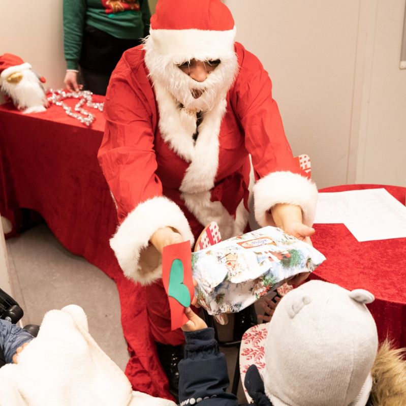 Jultomte ger en julkapp till ett barn på en av Stockholms Stadsmissions mötesplatser.